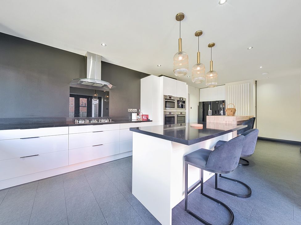 A kitchen with an island and bar stools at 8 Newmarket Road in Royston
