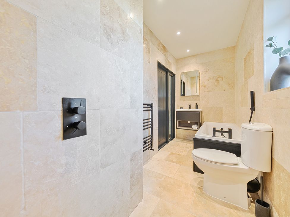 A bathroom with a bathtub and toilet at 8 Newmarket Road Royston