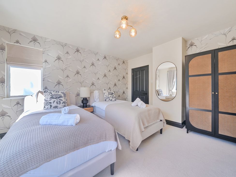 A bedroom with two beds and a wardrobe at 8 Newmarket Road in Royston