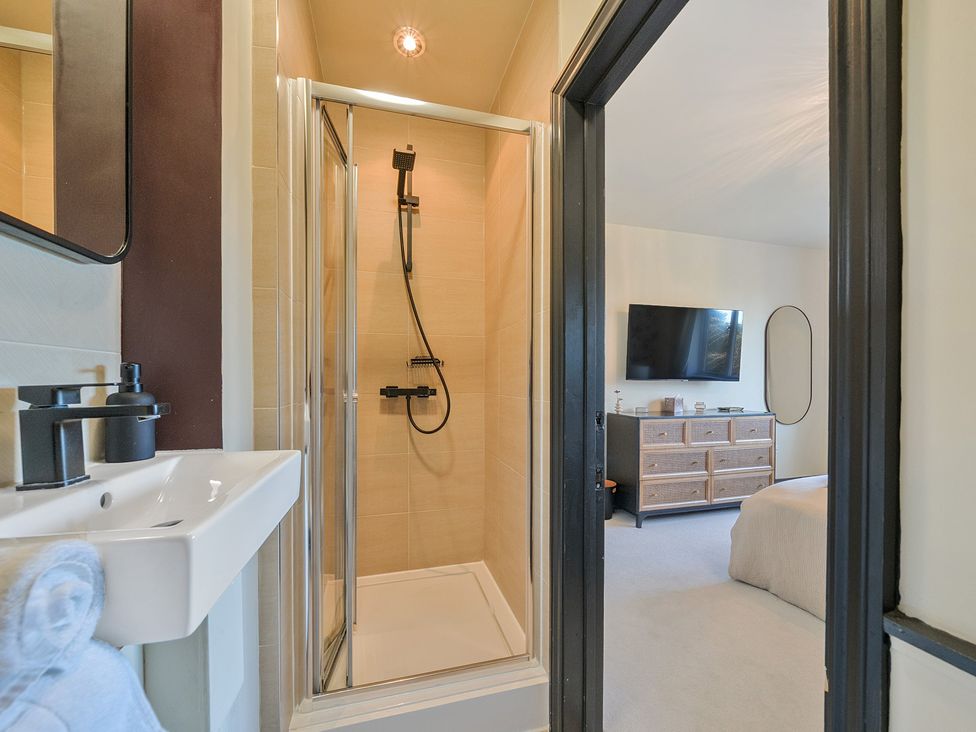 A bathroom with a shower and sink connected to a bedroom at 8 Newmarket Road Royston
