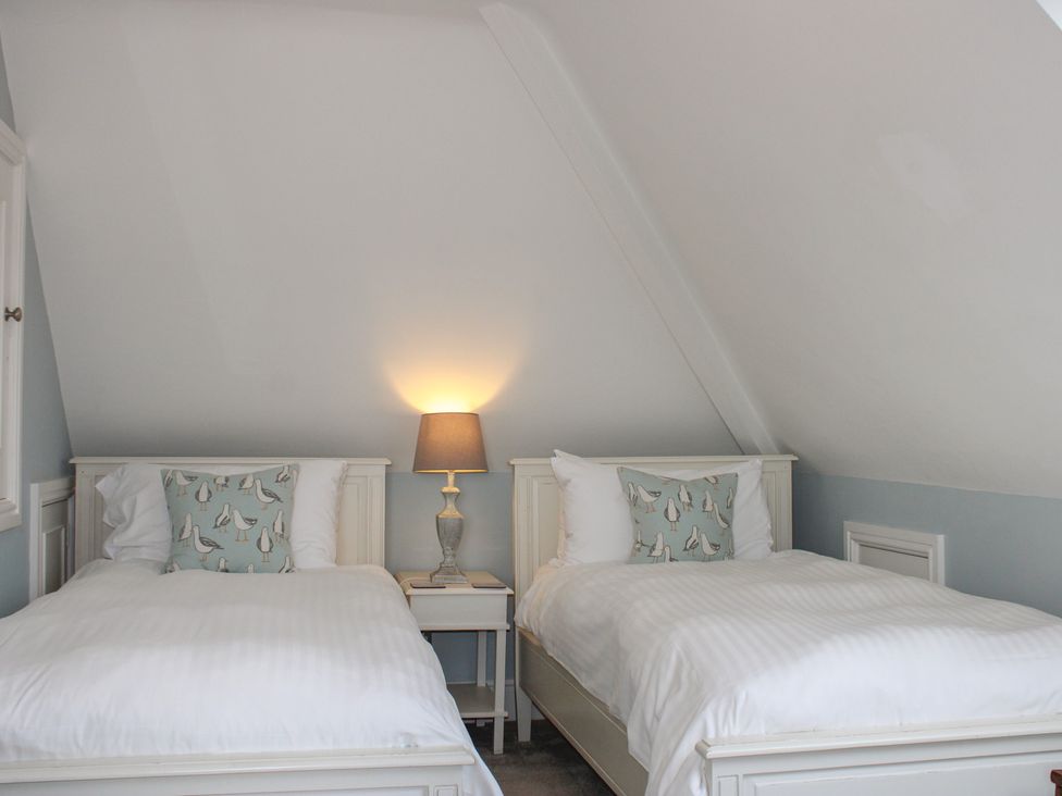 A bedroom with two single beds and a lamp at 2 Channel View Salcombe