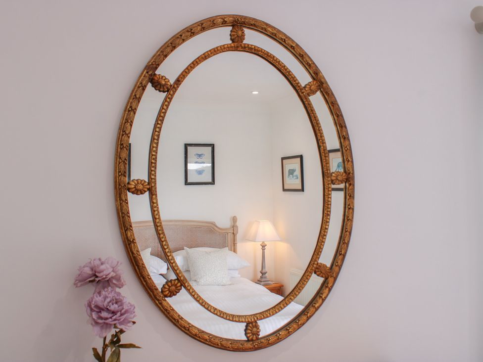 A bedroom with a mirror and lamp at 2 Channel View Salcombe