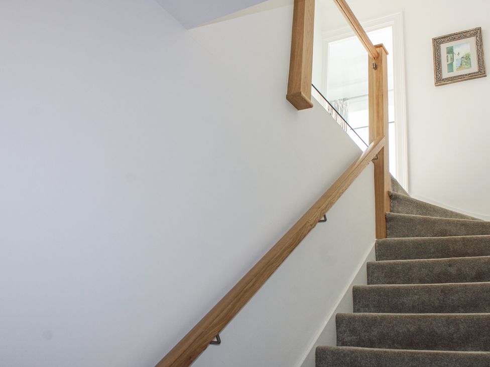 A staircase with a wooden handrail and a doorway at 2 Channel View Salcombe