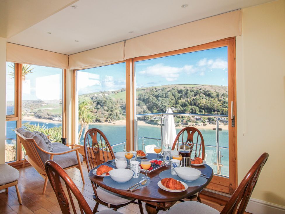A dining room with a table and a view at 2 Channel View in Salcombe