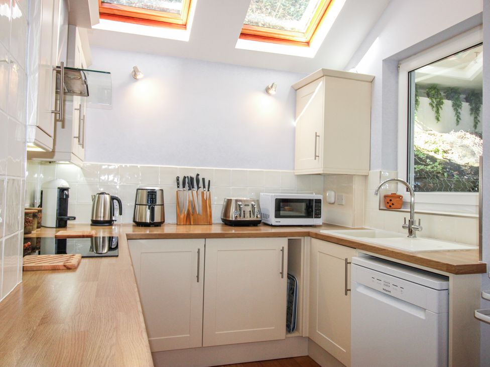 A kitchen with a sink, dishwasher, and microwave at 2 Channel View, Salcombe
