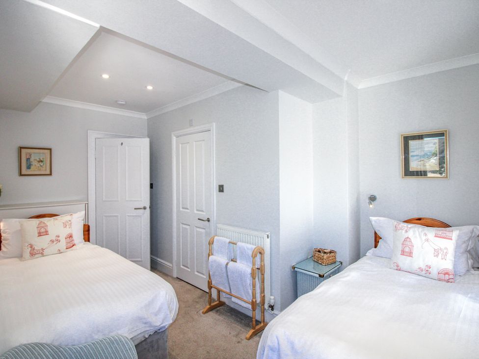 A bedroom with two beds and a towel holder at 2 Channel View Salcombe