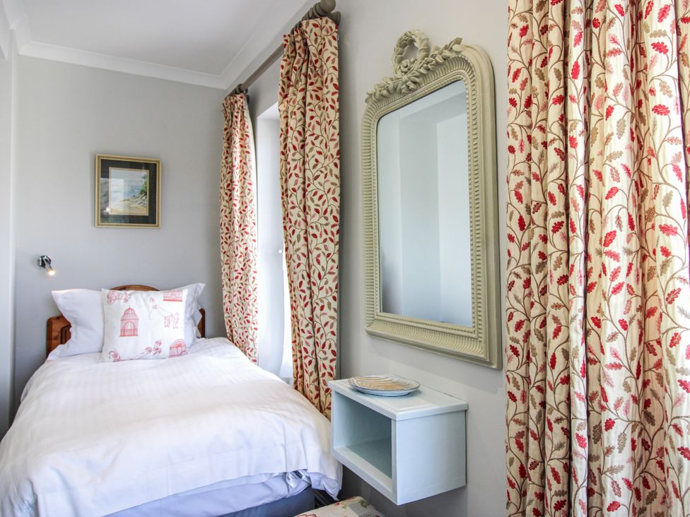 A bedroom with a single bed and decorative curtains at 2 Channel View, Salcombe