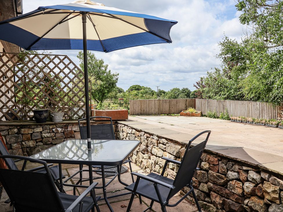 An outdoor seating area with a table and chairs at Sunbird Cottage in Biddulph