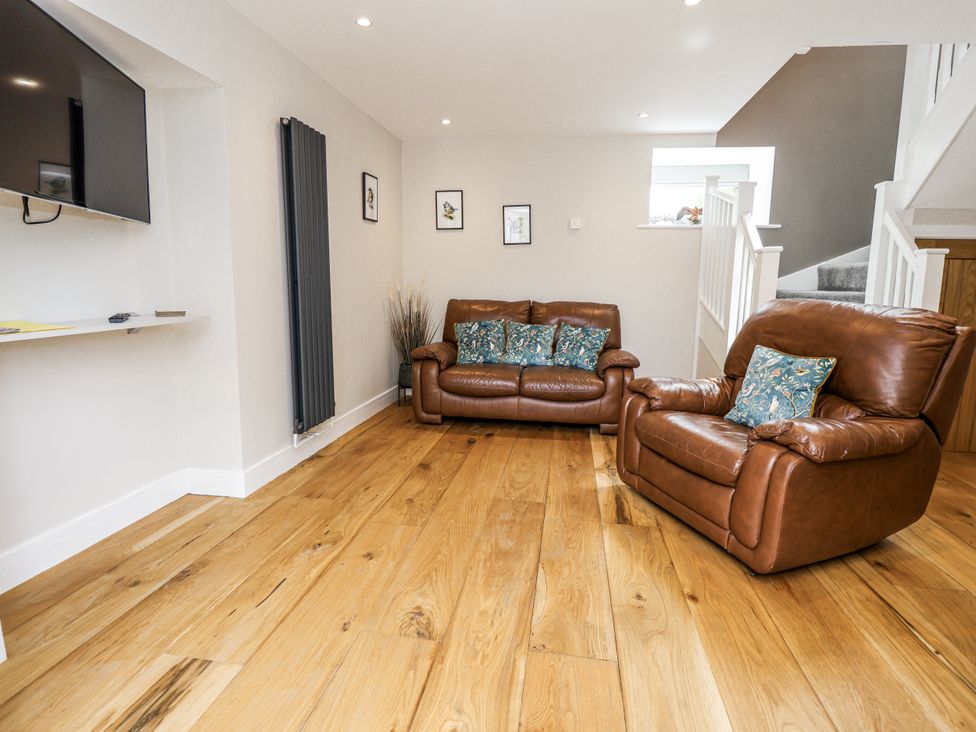 A living room with a sofa and armchair at Sunbird Cottage in Biddulph