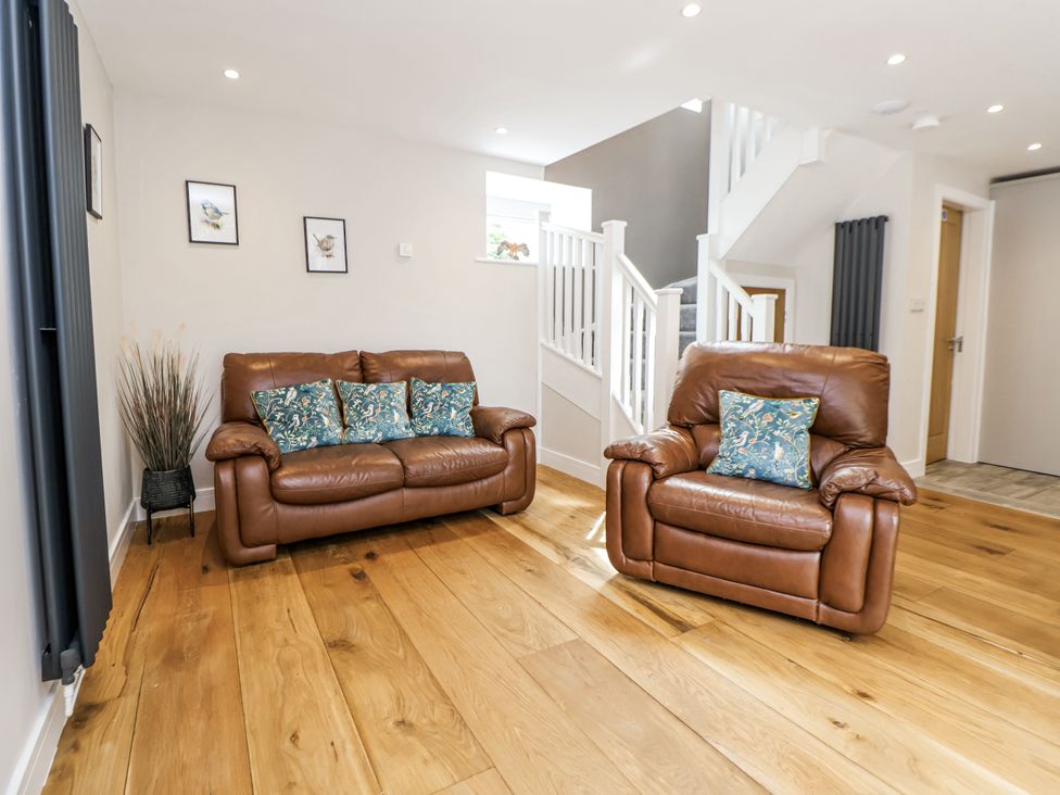 A living room with sofas and a staircase at Sunbird Cottage in Biddulph
