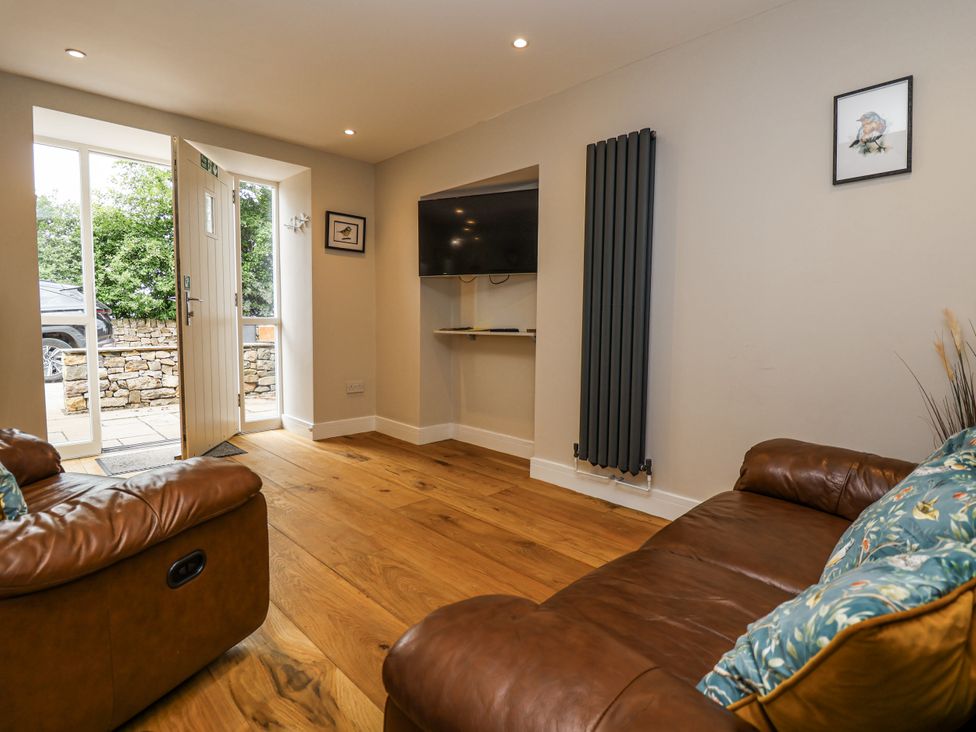 A living room with a sofa and television at Sunbird Cottage in Biddulph
