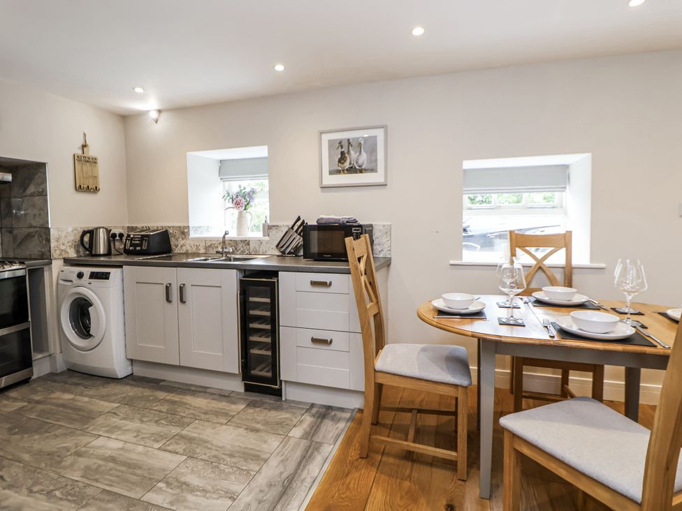 A kitchen with appliances and dining area at Sunbird Cottage in Biddulph