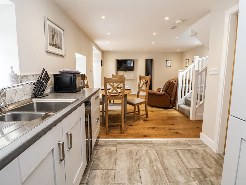 A kitchen with dining area and living room view at Sunbird Cottage in Biddulph