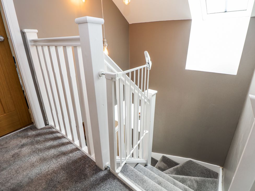 A staircase with a handrail and a window at Sunbird Cottage in Biddulph
