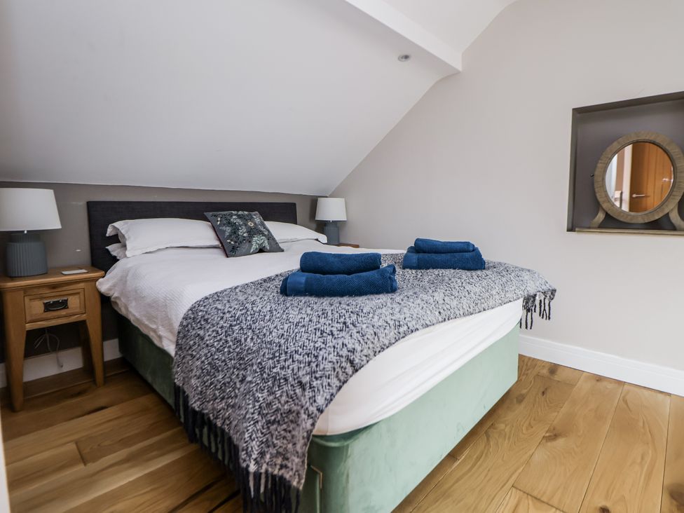 A bedroom with a bed and nightstand at Sunbird Cottage in Biddulph