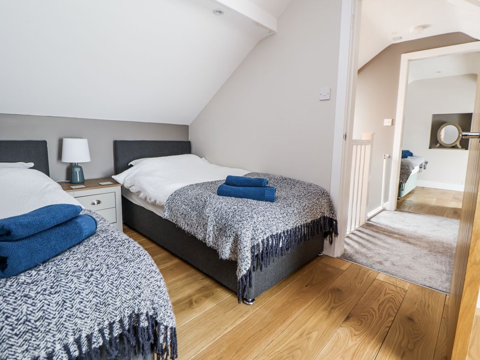 A bedroom with two beds and a nightstand at Sunbird Cottage in Biddulph