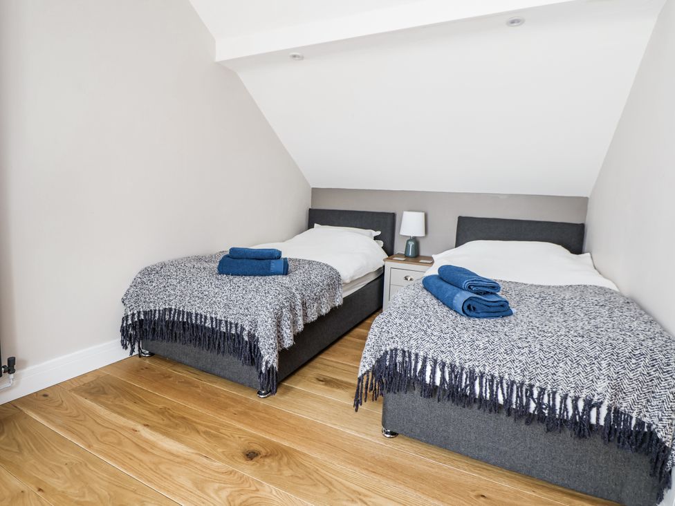A bedroom with two beds and a bedside table at Sunbird Cottage in Biddulph
