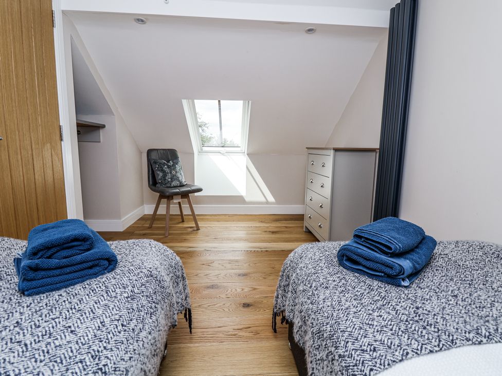 A bedroom with two beds and a chair at Sunbird Cottage in Biddulph