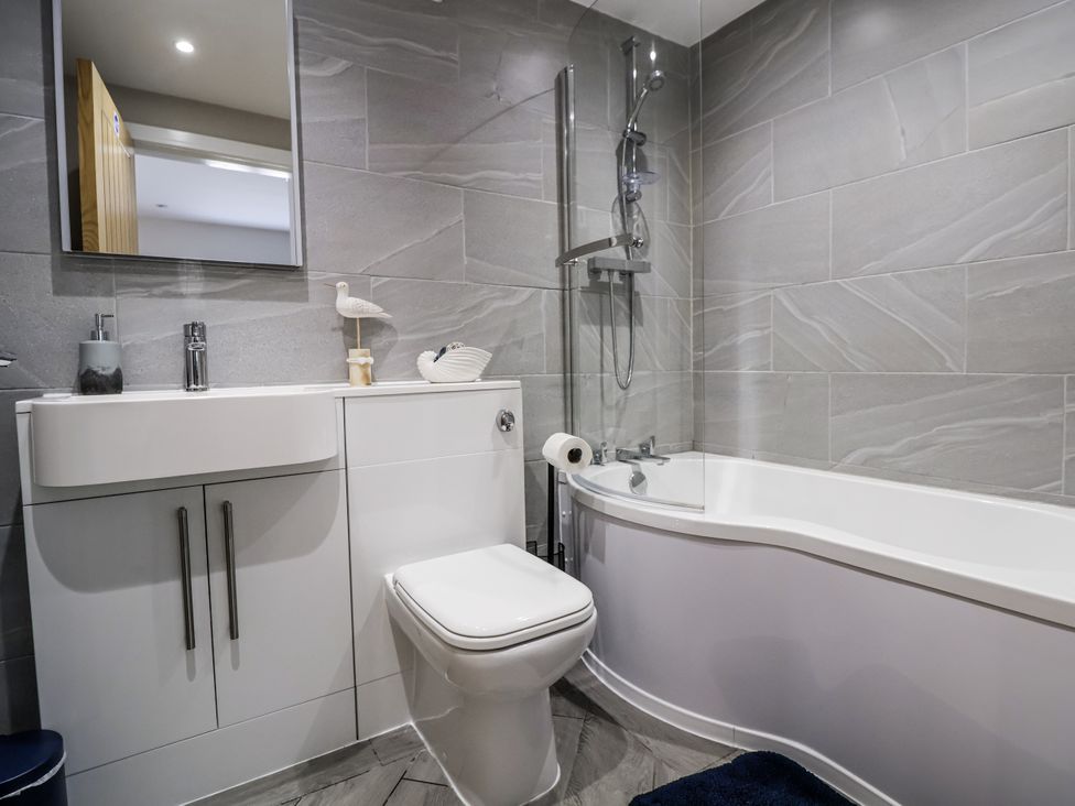 A bathroom with a sink, toilet, bathtub, and shower at Sunbird Cottage in Biddulph