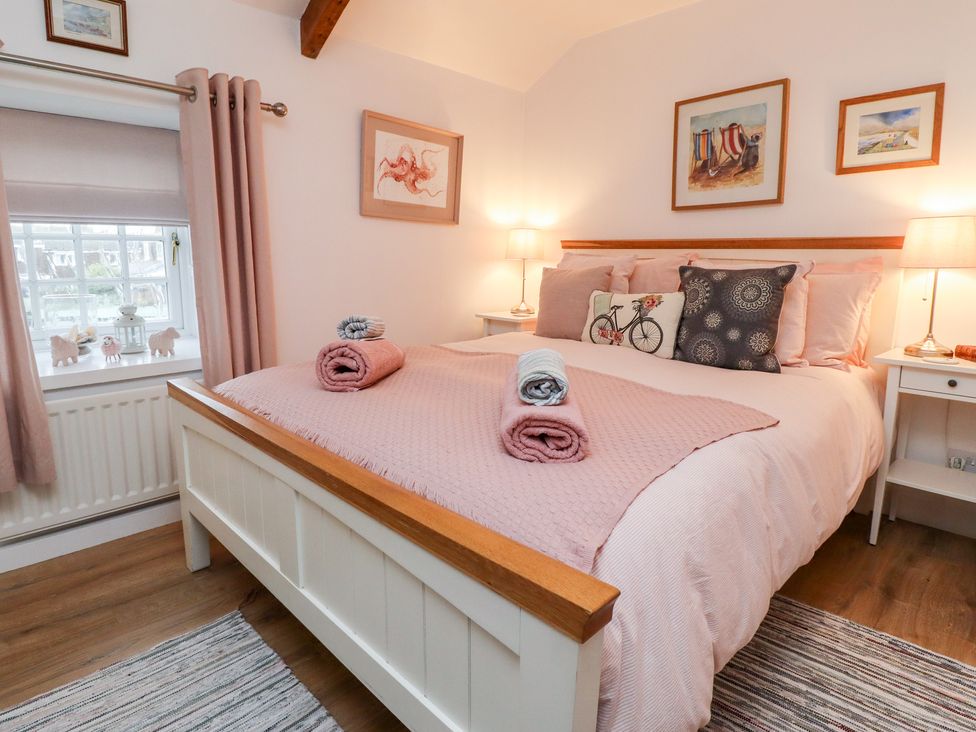 A bedroom with a bed with folded towels on it bedside tables with lamps and framed pictures on the walls at Seahares in Seahouses