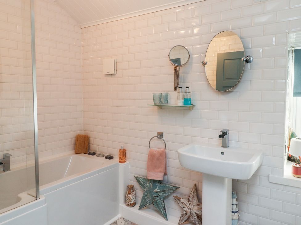 A bathroom with a bathtub sink two mirrors and star-shaped decorations at Seahares in Seahouses