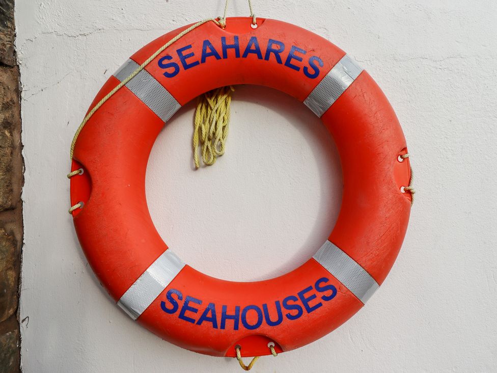 An orange life buoy with rope and the words seahares and seahouses on a white wall at Seahares in Seahouses