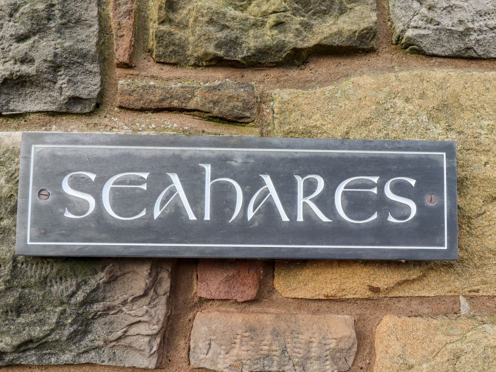 A sign with the name seahares mounted on a stone wall at Seahares in Seahouses