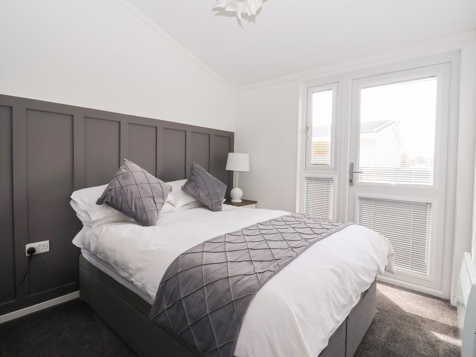 A bedroom with a double bed and a bedside lamp at Bonny Bay in Wilsthorpe near Bridlington