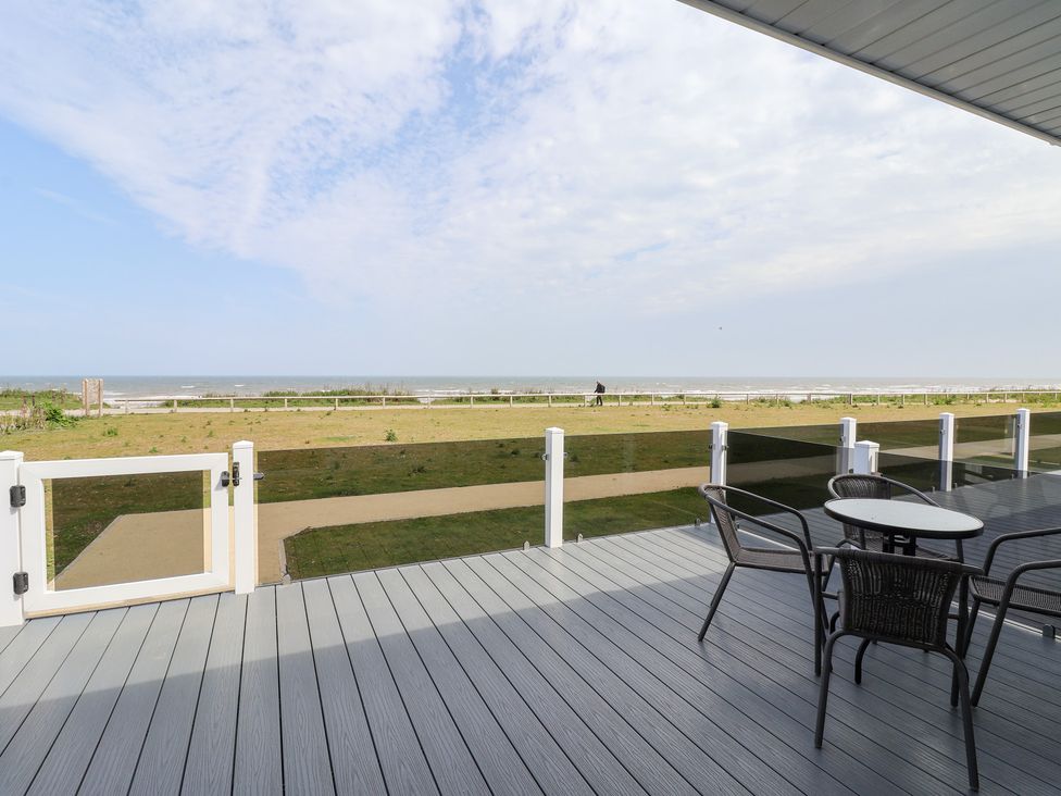 An outdoor area with a table and chairs overlooking the beach at Bonny Bay Wilsthorpe near Bridlington
