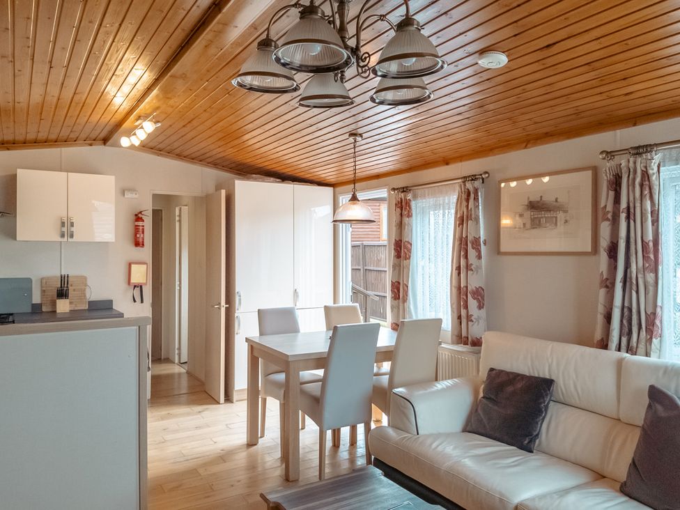 A living room with a kitchen area and a dining table at Willow in Swanage