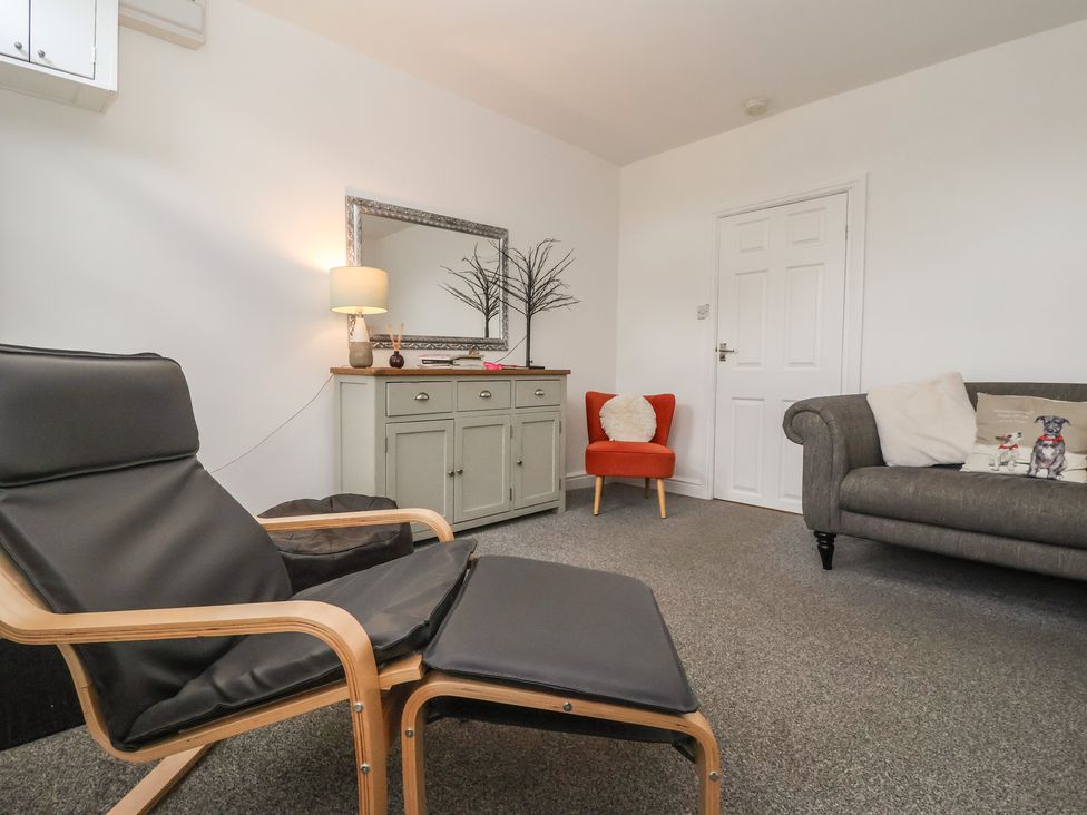 A living room with a chair, sofa, and cabinet at Bluebell Cottage in Brayton
