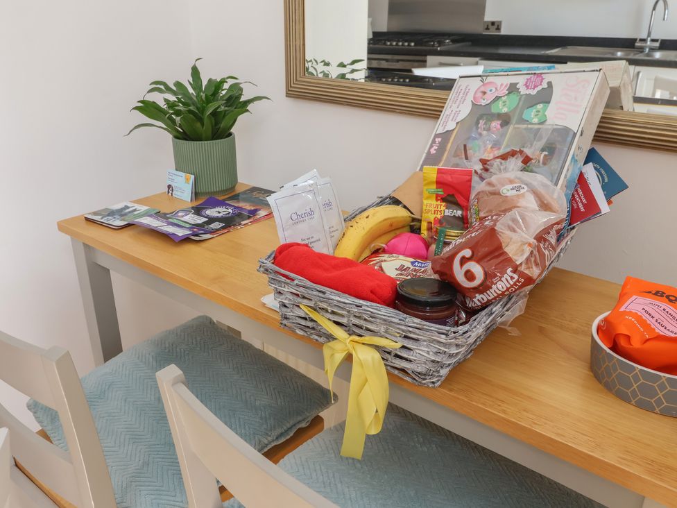 A table with a plant and a basket filled with snacks at Bluebell Cottage in Brayton