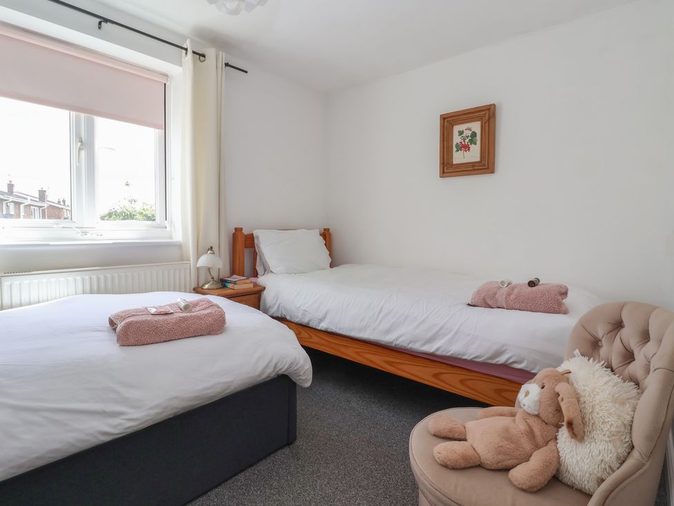 A bedroom with two beds and a chair at Bluebell Cottage in Brayton