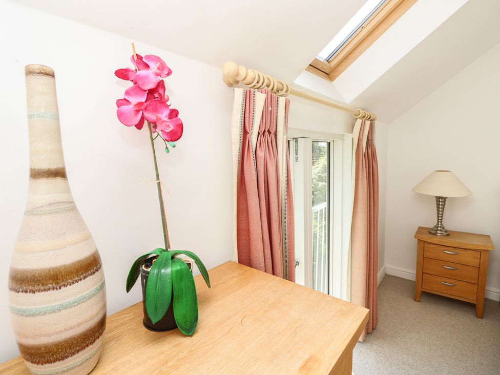 A bedroom with a vase, lamp, curtains and a side table at Delaware M2 in Yarmouth