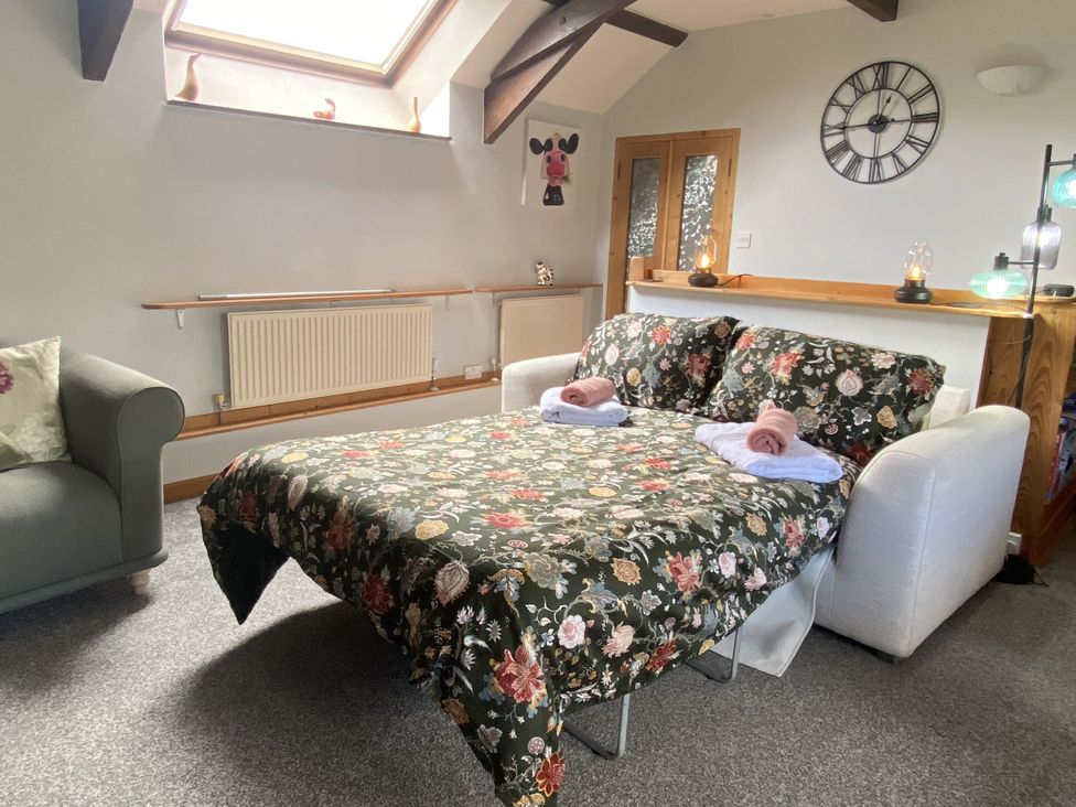 A living room with a sofa bed and decorative items at Foxglove Barn South Brent