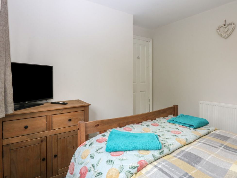 A bedroom with a television on a dresser and towels on the bed at 2 Trem Y Don in Colwyn Bay