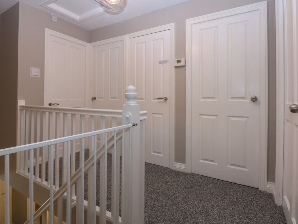 A hallway with multiple doors and a handrail at 2 Trem Y Don in Colwyn Bay