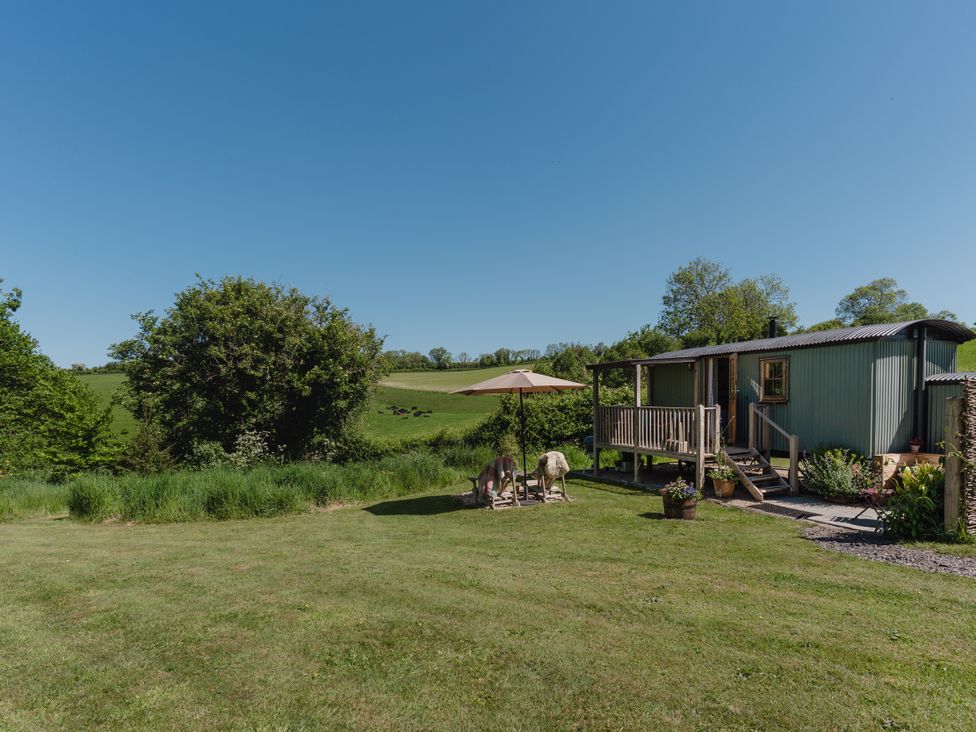 A garden with a mobile home and deck at Hurdlemakers Hut in Piddletrenthide