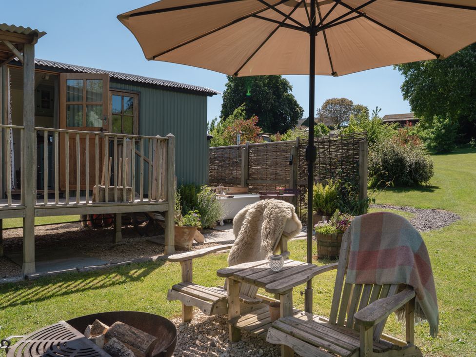 A garden area with chairs and an umbrella at Hurdlemakers Hut in Piddletrenthide