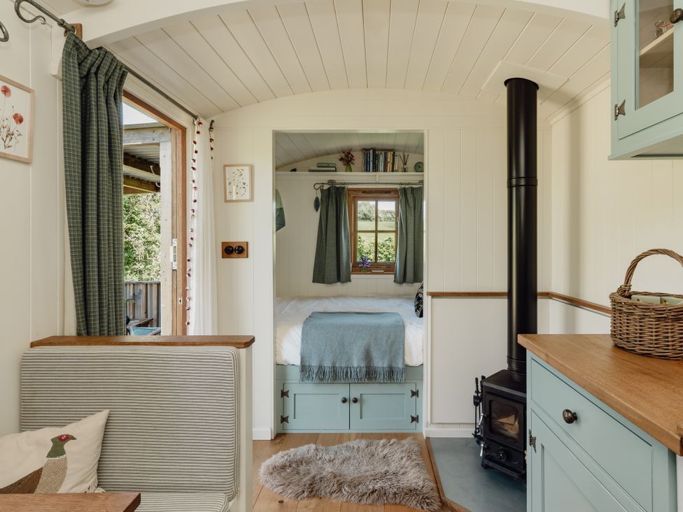 A living room with a bed and stove at Hurdlemakers Hut in Piddletrenthide