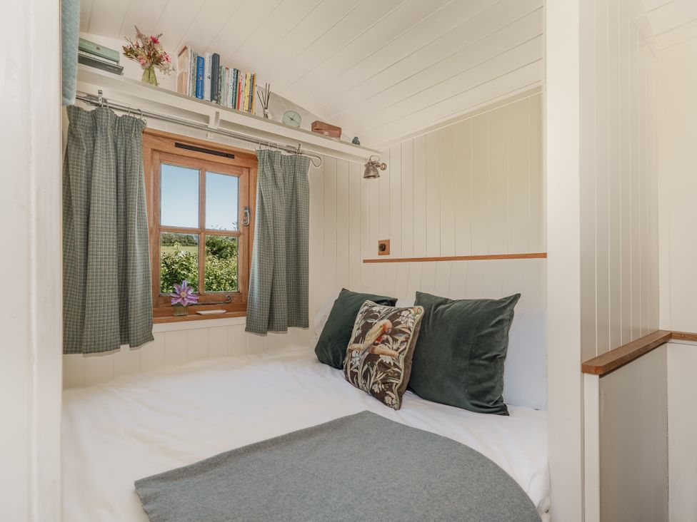 A bedroom with a bed and window at Hurdlemakers Hut in Piddletrenthide