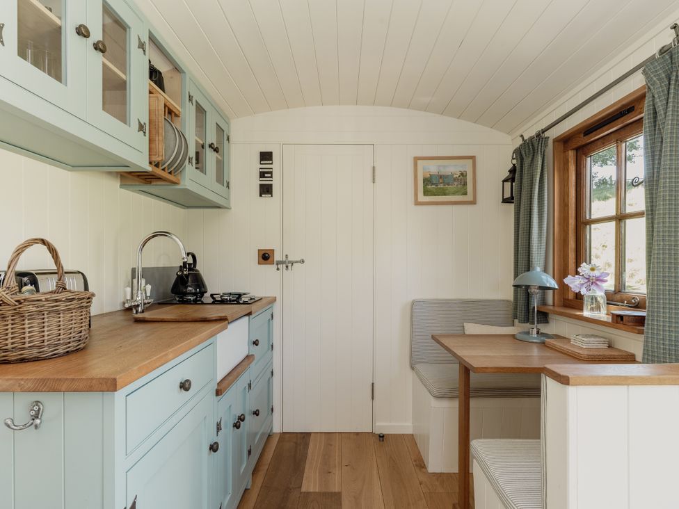 A kitchen with cabinets and a dining table at Hurdlemakers Hut in Piddletrenthide