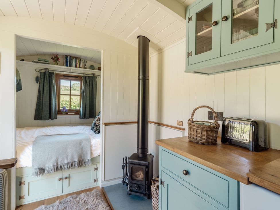 A living room with a bed and a stove at Hurdlemakers Hut in Piddletrenthide