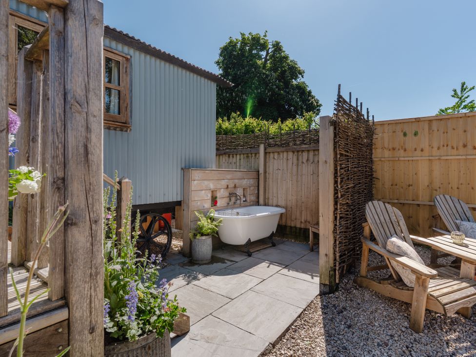 An outdoor area with a bath tub and seating at Spindleberry Hut in Piddletrenthide