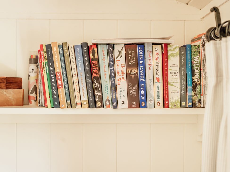 A shelf with books and a wooden box at Spindleberry Hut in Piddletrenthide