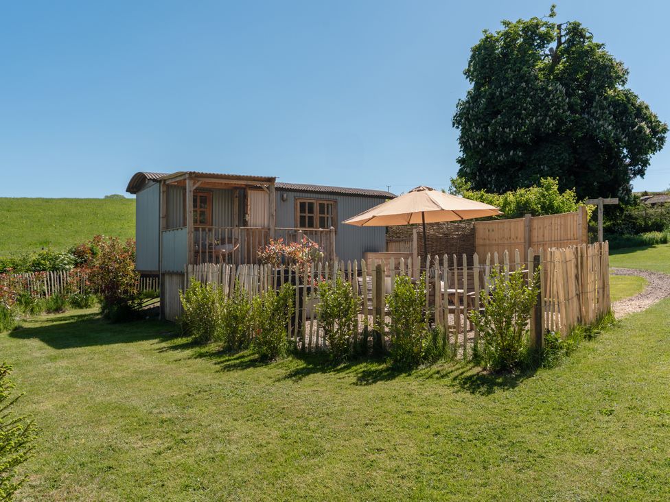 A garden with a shepherd's hut and patio area at Spindleberry Hut in Piddletrenthide