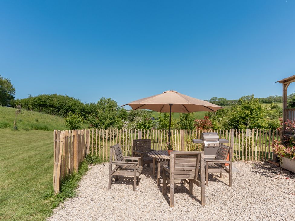 An outdoor area with a table, chairs, and a barbecue at Spindleberry Hut in Piddletrenthide