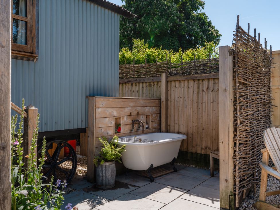 An outdoor area with a bath tub and wooden fence at Spindleberry Hut in Piddletrenthide