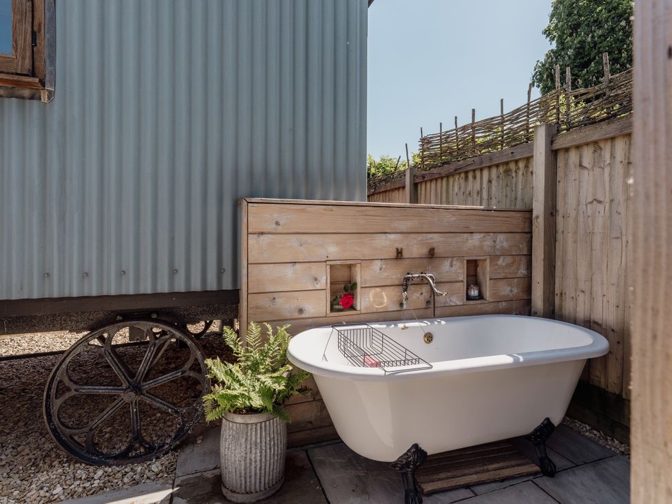 An outdoor bathing area with a bathtub and wooden structure at Spindleberry Hut in Piddletrenthide