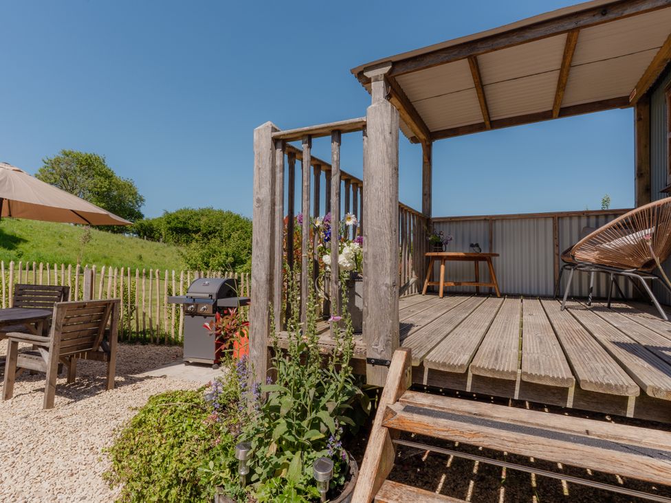 An outdoor area with a wooden deck and table at Spindleberry Hut in Piddletrenthide